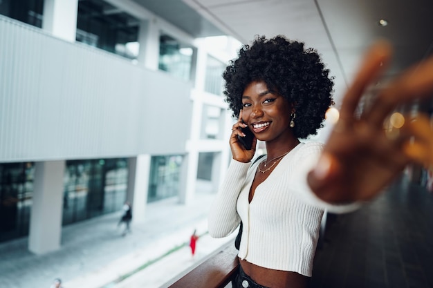 Retrato de una joven africana feliz hablando por celular en la ciudad