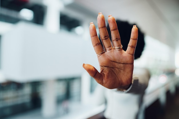 Retrato de una joven africana seria que muestra un gesto de parada con la palma de la mano en el fondo urbano