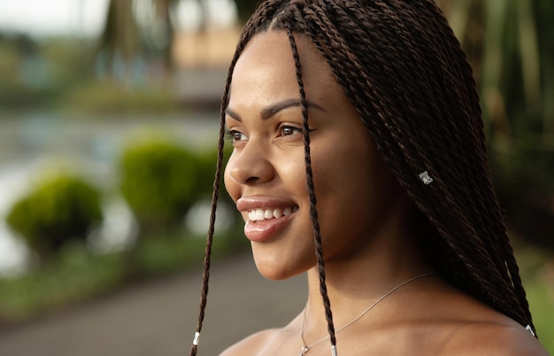 Retrato de una joven africana sonriente con coletas con rastas en la cabeza.