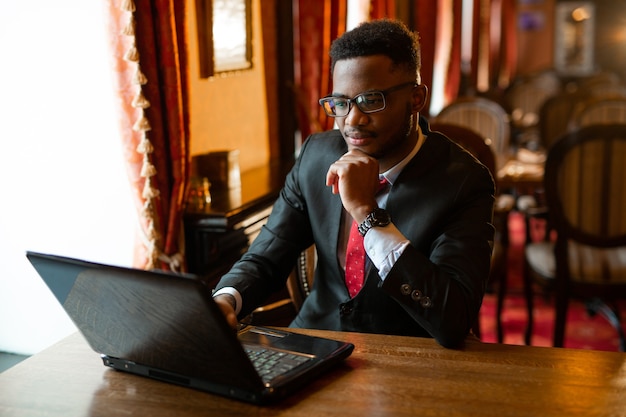 Retrato de un joven africano guapo con gafas con portátil