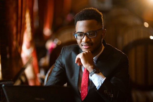 Retrato de un joven africano guapo con gafas con portátil