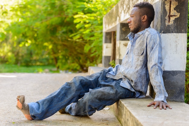 Retrato de joven africano sin hogar en el puente en las calles al aire libre