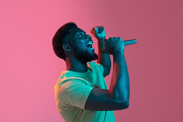 Retrato de un joven africano sobre fondo de estudio rosa en neón Concepto de emociones humanas expresión facial anuncio de ventas para jóvenes