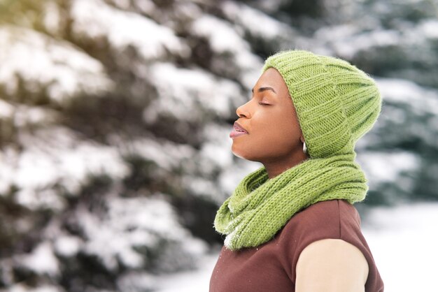 Foto retrato de una joven afroamericana feliz en un día nevado de invierno en el parque de nieve sonriendo