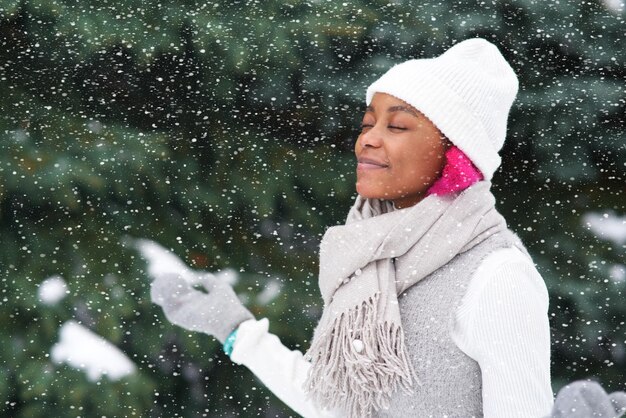 Retrato de una joven afroamericana feliz en un día nevado de invierno en el parque de nieve sonrisa