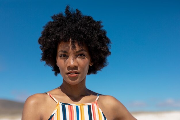 Retrato de una joven afroamericana segura de sí misma con peinado afro contra el cielo azul
