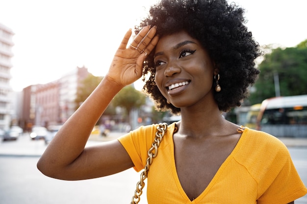 Retrato de una joven afroamericana sonriendo de pie en la ciudad