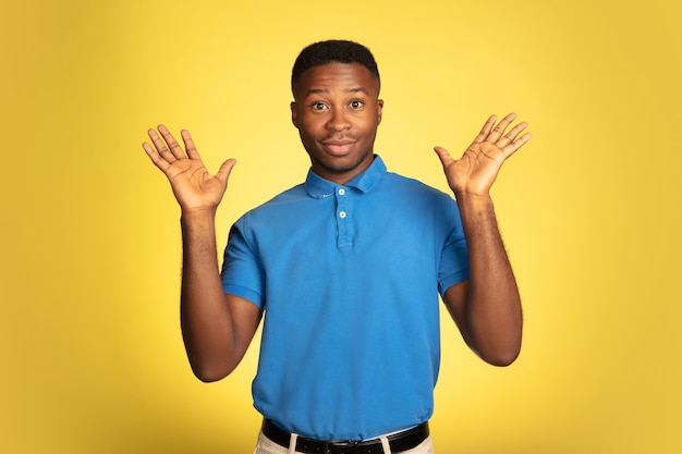 Retrato de joven afroamericano aislado sobre fondo amarillo de estudio, expresión facial.