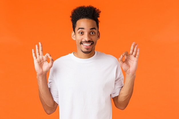 Retrato joven afroamericano en camiseta blanca mostrando gesto.