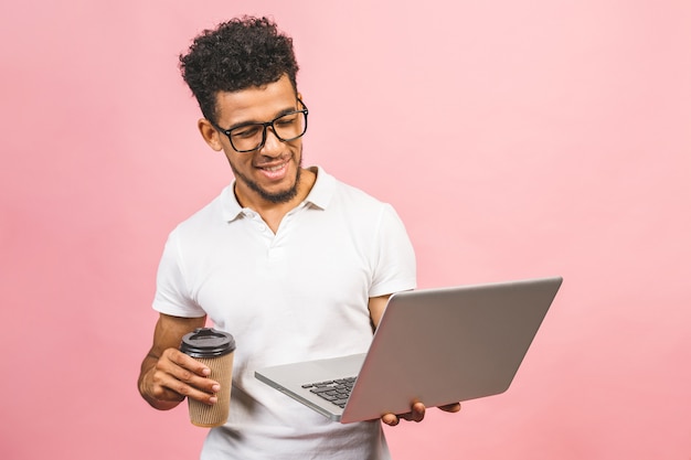 Retrato de joven afroamericano casual guapo tomando café mientras sostiene el portátil