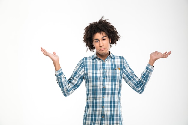 Retrato de un joven afroamericano encogiéndose de hombros aislado en un fondo blanco