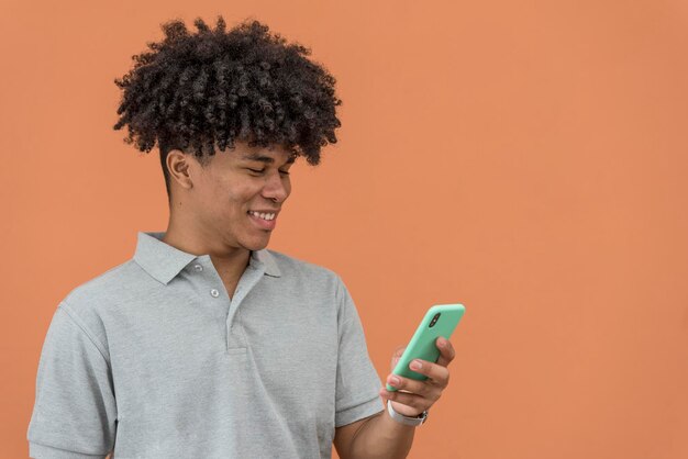 Retrato de un joven afroamericano sonriendo y mirando su teléfono, Panamá