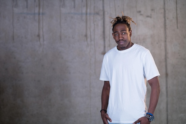 retrato de un joven afroamericano sonriente hombre de negocios casual parado frente a un muro de hormigón en una nueva oficina de inicio