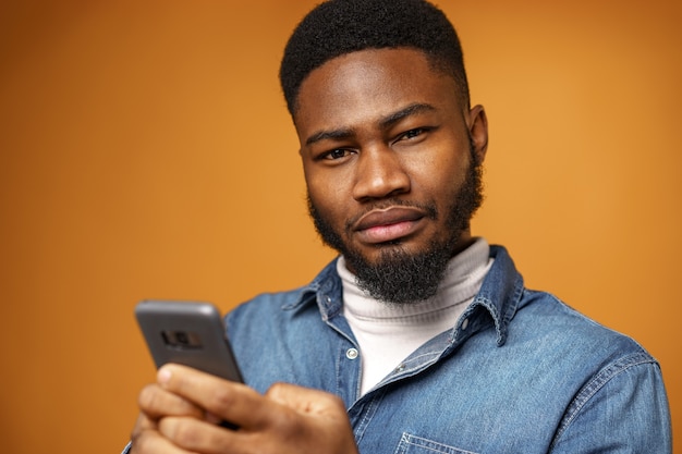 Retrato de joven afroamericano con su smartphone contra