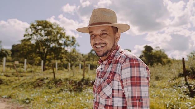 Retrato de un joven agricultor con camisa informal y sombrero en la granja