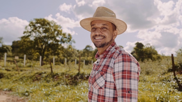 Retrato de un joven agricultor con camisa informal y sombrero en la granja