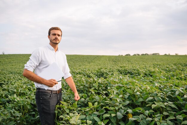 Retrato de joven agricultor en campo de soja.