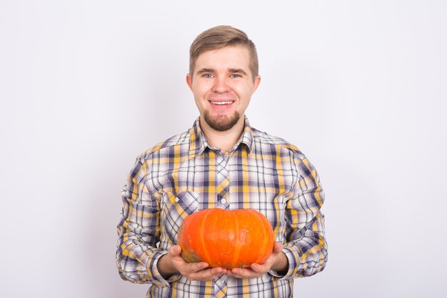 Retrato de un joven agricultor sosteniendo una calabaza en un estudio de fondo claro