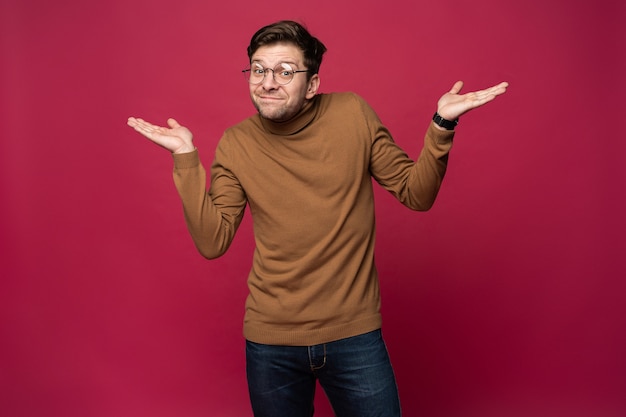 Retrato de un joven alegre apuntando con el dedo hacia el espacio de la copia en la palma de su mano aislado sobre fondo rosa.