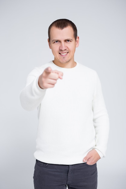 Retrato de joven alegre apuntando con su dedo hacia usted