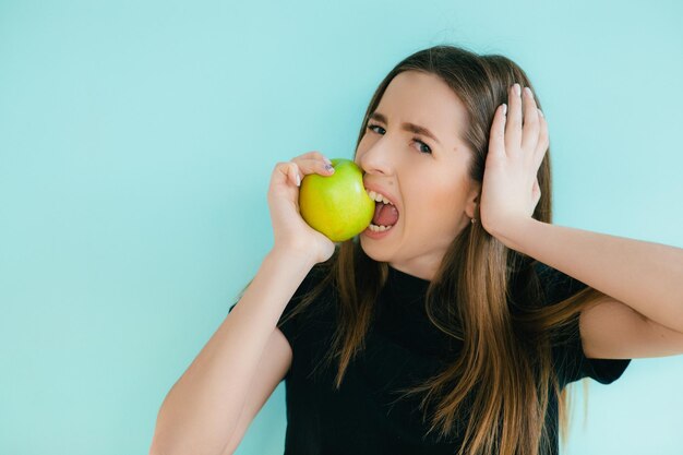 Retrato de una joven alegre comiendo manzana verde