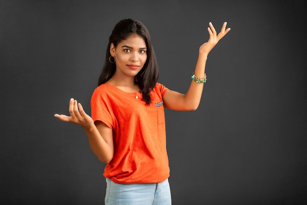 Retrato de una joven alegre y exitosa sosteniendo y presentando algo a mano con una cara sonriente feliz