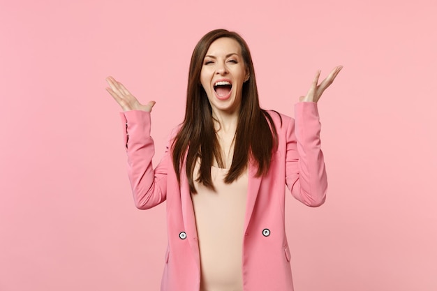 Retrato de una joven alegre y feliz gritando con chaqueta, esparciendo las manos aisladas en un fondo de pared rosa pastel en el estudio. Emociones sinceras de la gente, concepto de estilo de vida. Simulacros de espacio de copia.