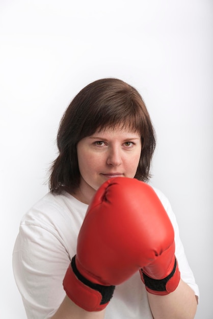 Retrato de una joven alegre con guantes de boxeo rojos. Boxeadora sobre fondo blanco.