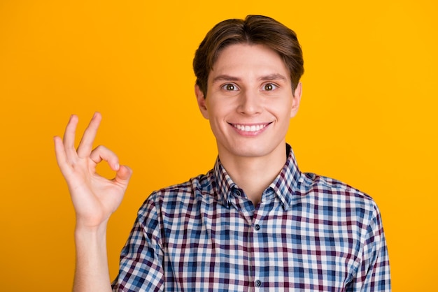 Retrato de un joven alegre que muestra un gesto correcto aislado en un fondo de color brillante