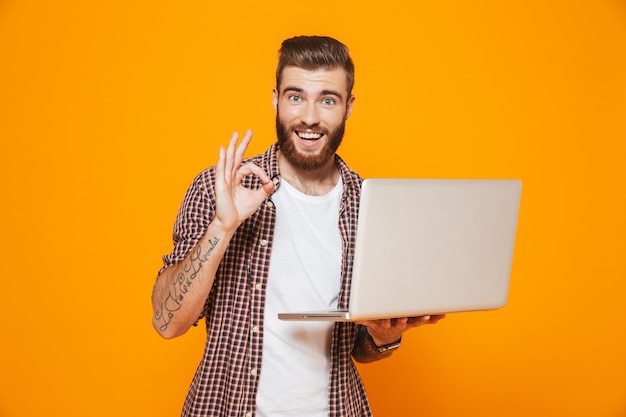 Retrato de un joven alegre con ropa casual con ordenador portátil