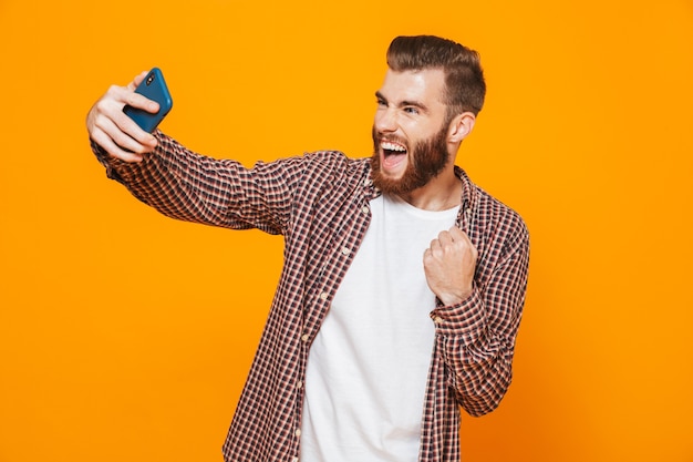 Retrato de un joven alegre con ropa casual tomando un selfie