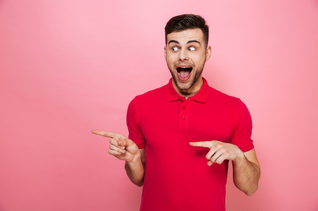 Retrato de un joven alegre señalando con el dedo