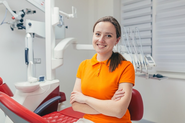 Retrato joven amable dentista sonriendo y mirando al frente en un consultorio dental moderno