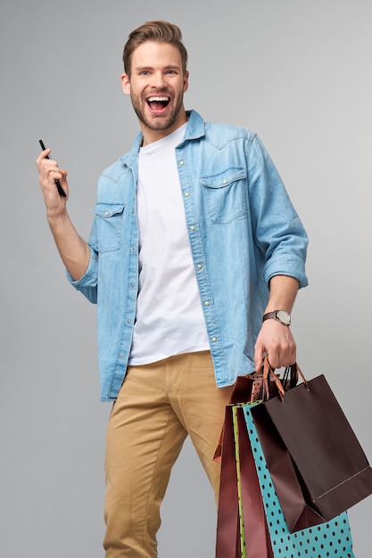 Retrato de un joven apuesto con bolsas de la compra.