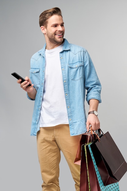 Retrato de un joven apuesto con bolsas de la compra.