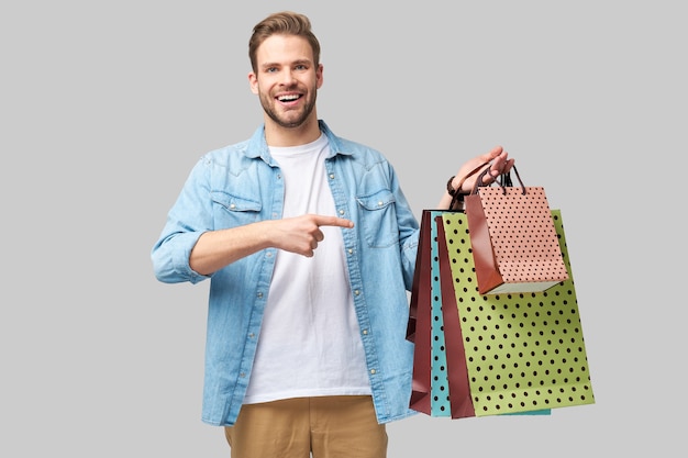 Foto retrato de un joven apuesto con bolsas de la compra.