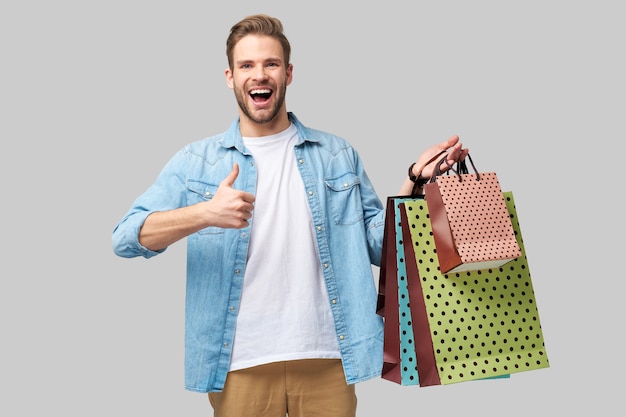 Foto retrato de un joven apuesto con bolsas de la compra.