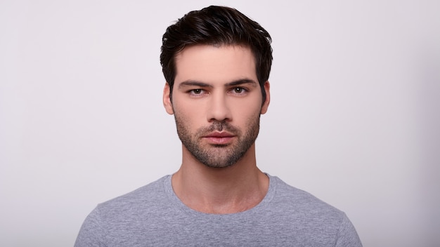 Foto retrato de un joven apuesto en una camiseta gris.