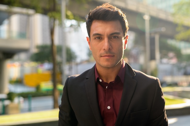 Retrato de joven apuesto empresario hispano en las calles de la ciudad al aire libre