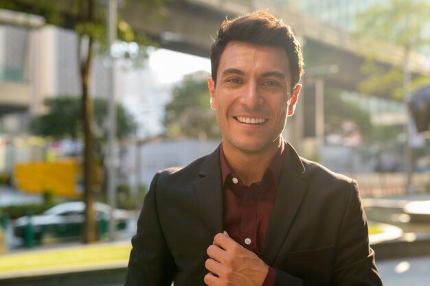 Retrato de joven apuesto empresario hispano en las calles de la ciudad al aire libre