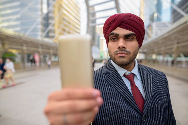 Retrato de joven apuesto empresario sij indio con turbante mientras explora la ciudad de Bangkok, Tailandia