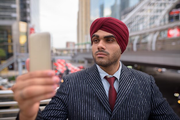 Retrato de joven apuesto empresario sij indio con turbante mientras explora la ciudad de Bangkok, Tailandia