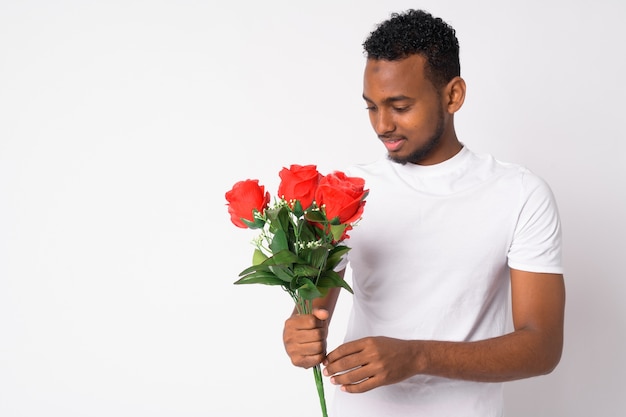 Retrato de joven apuesto hombre africano listo para el día de San Valentín contra la pared blanca