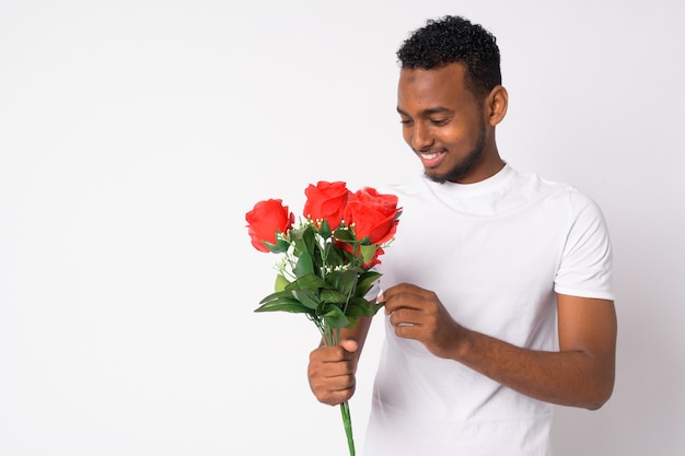 Retrato de joven apuesto hombre africano listo para el día de San Valentín contra la pared blanca