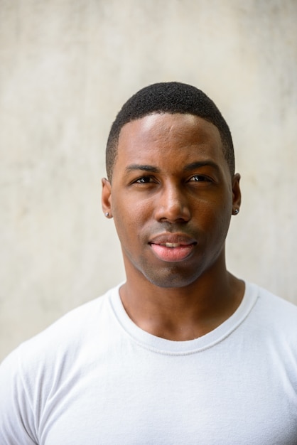 Foto retrato de joven apuesto hombre africano musculoso contra el muro de hormigón al aire libre