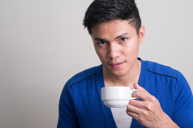 Retrato de joven apuesto hombre asiático tomando café