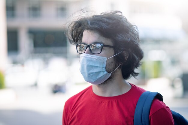 Foto retrato de un joven apuesto hombre caucásico con gafas y una máscara