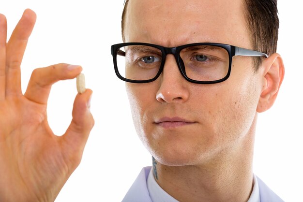 Retrato de joven apuesto médico con anteojos sosteniendo pastillas de medicina