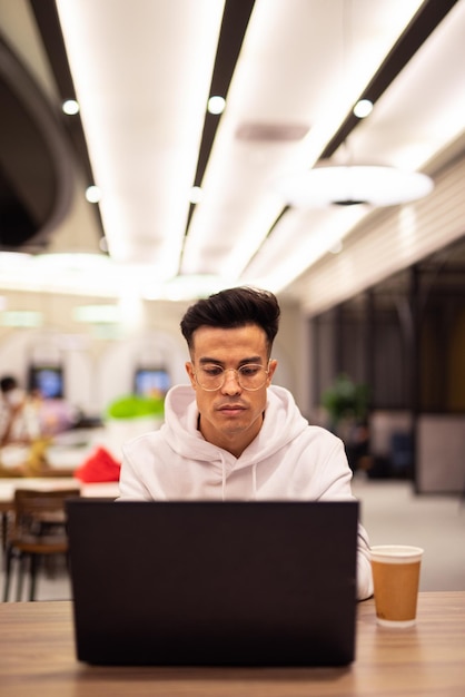 Retrato de un joven apuesto que usa una laptop en la cafetería