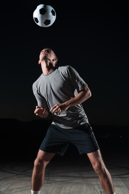 retrato de un joven apuesto y talentoso jugador de fútbol en una calle jugando con una pelota de fútbol. foto de alta calidad